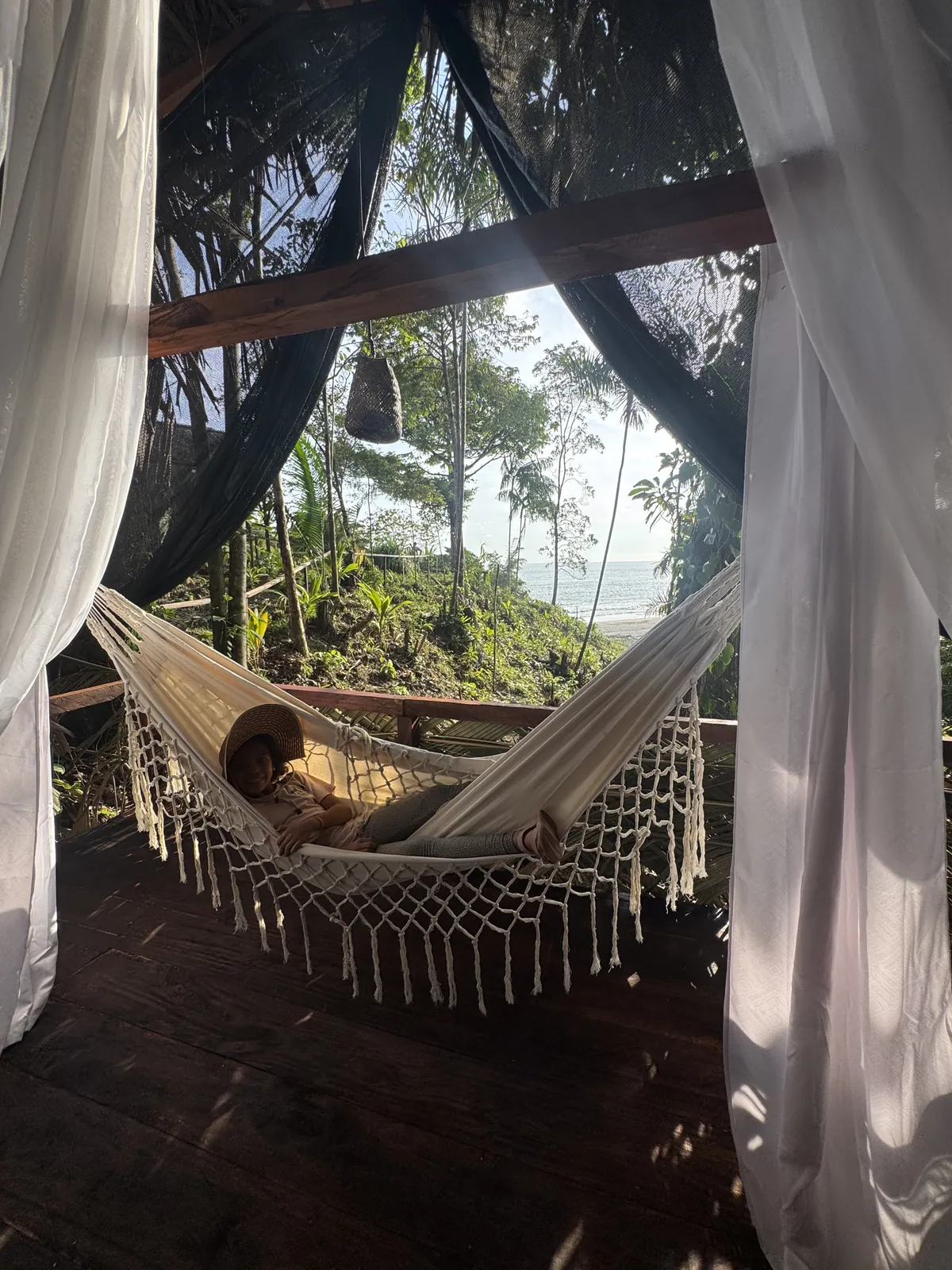 Hamaca del Glamping de LUX entre cortinas blancas con vista al Pacífico