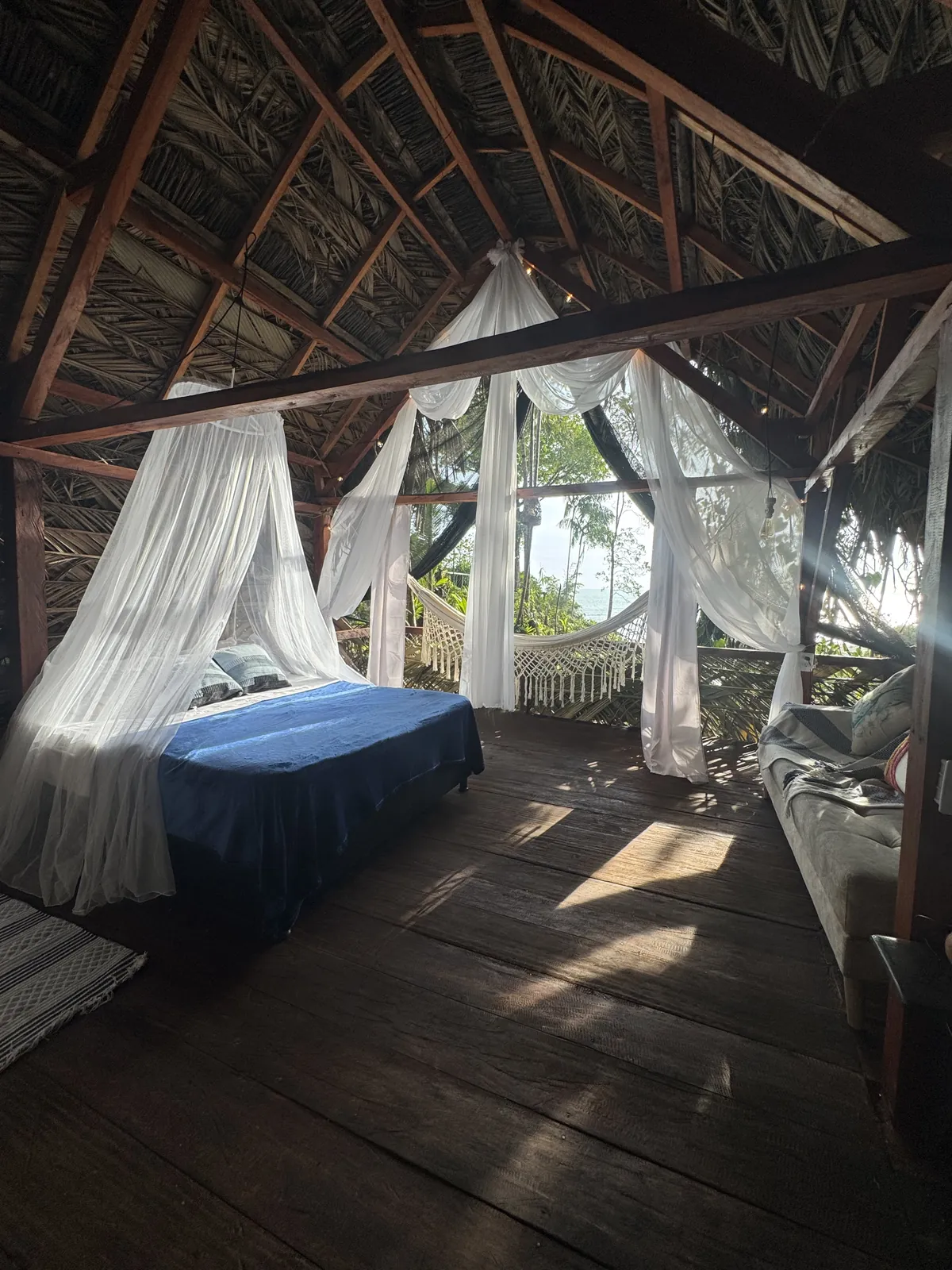 Vista general del Glamping de LUX con cama y cortinas al mar