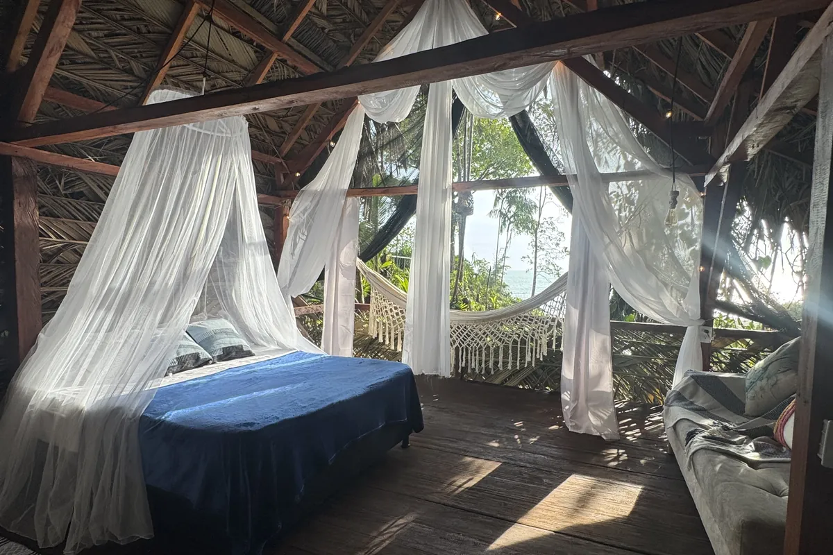 Glamping de LUX con cama, cortinas blancas y vista al mar del Pacífico