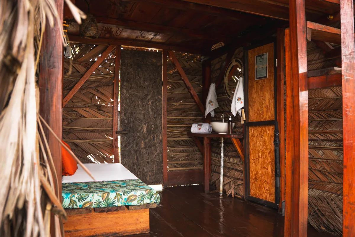 Interior del Mini Nativo con cama, baño y techo de palma