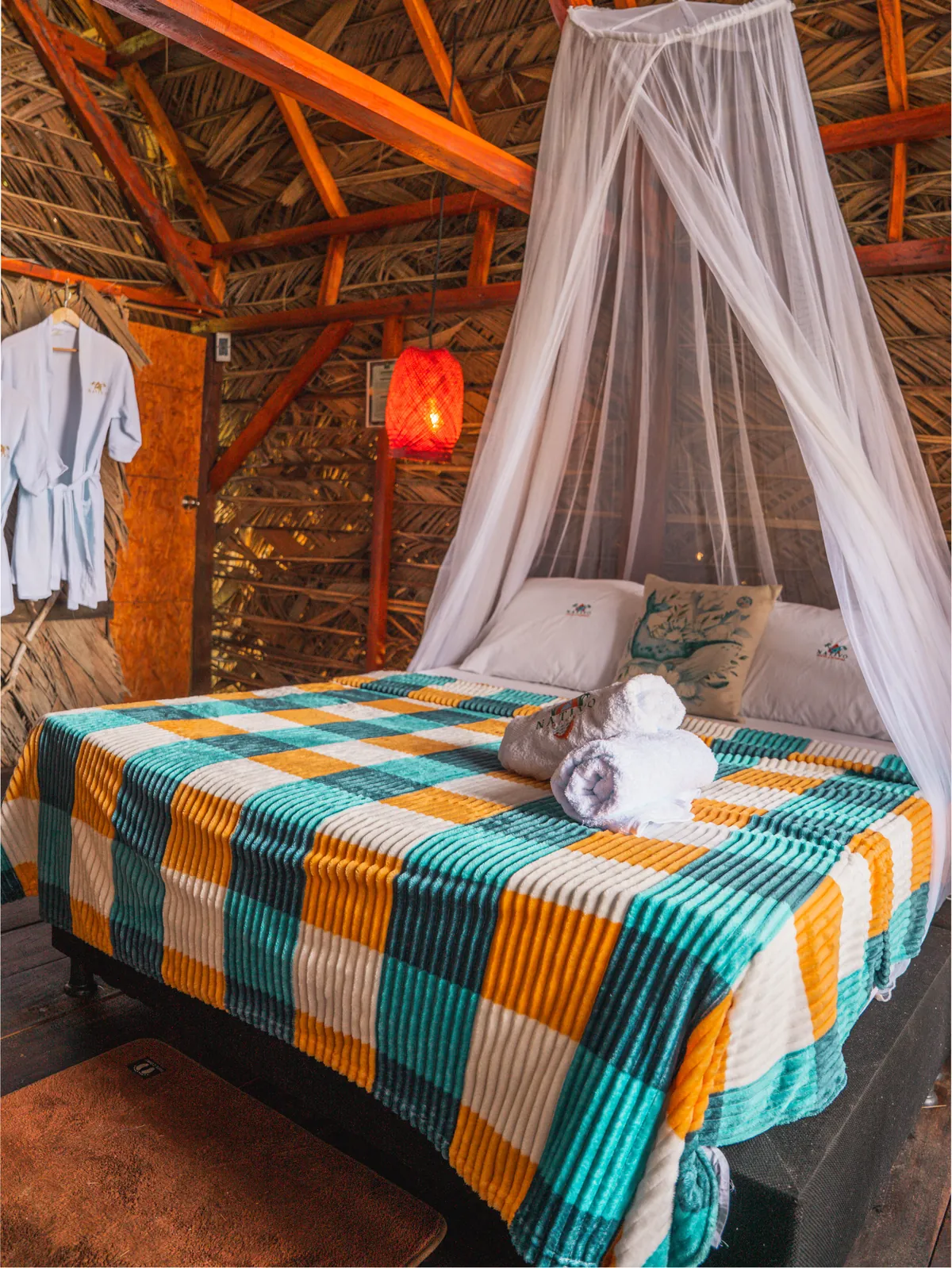 Cama del Bungalow Premium con mosquitero, lámpara roja y batas