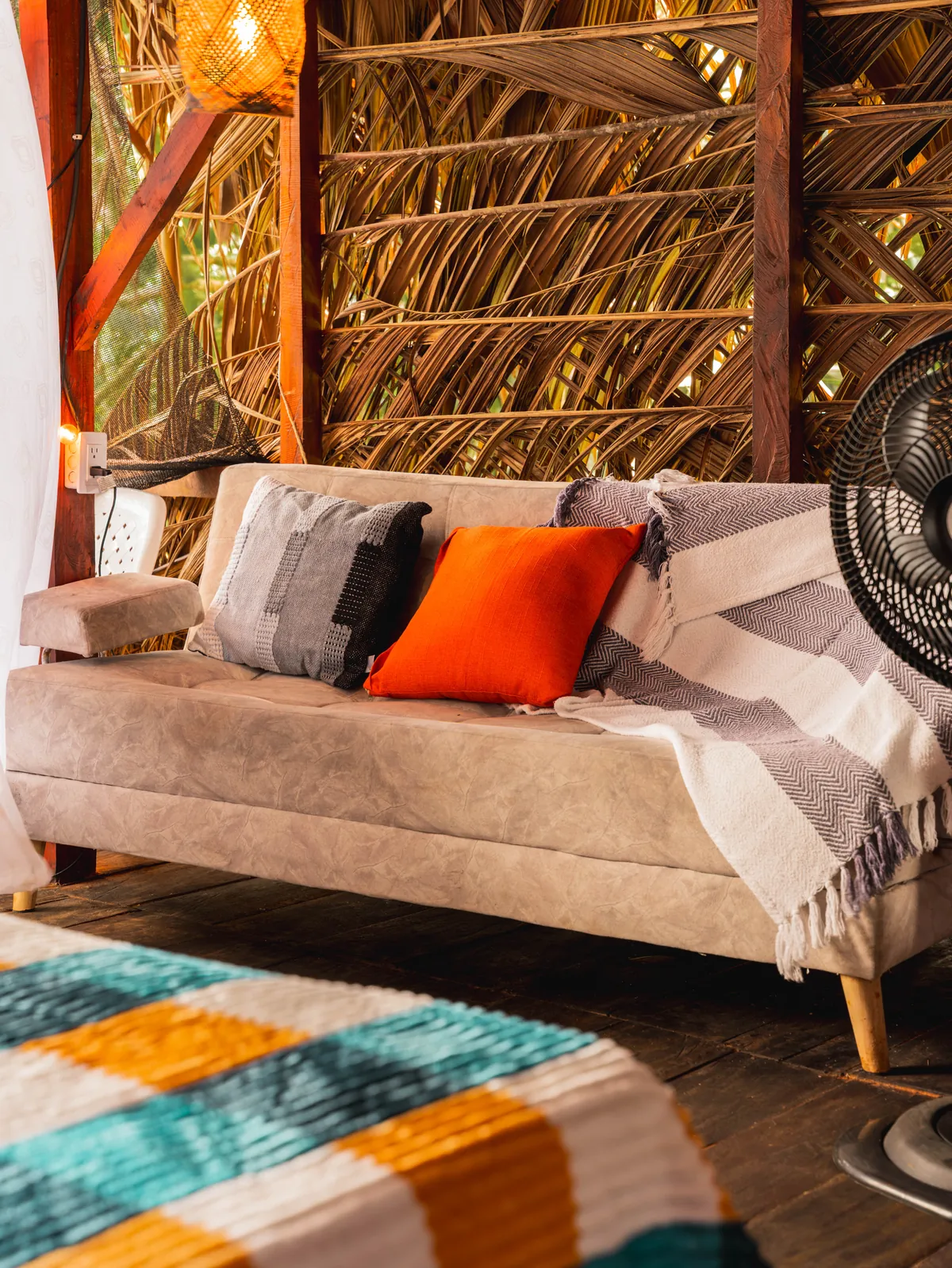 Sofá con cojín naranja junto a la cama del Bungalow Premium