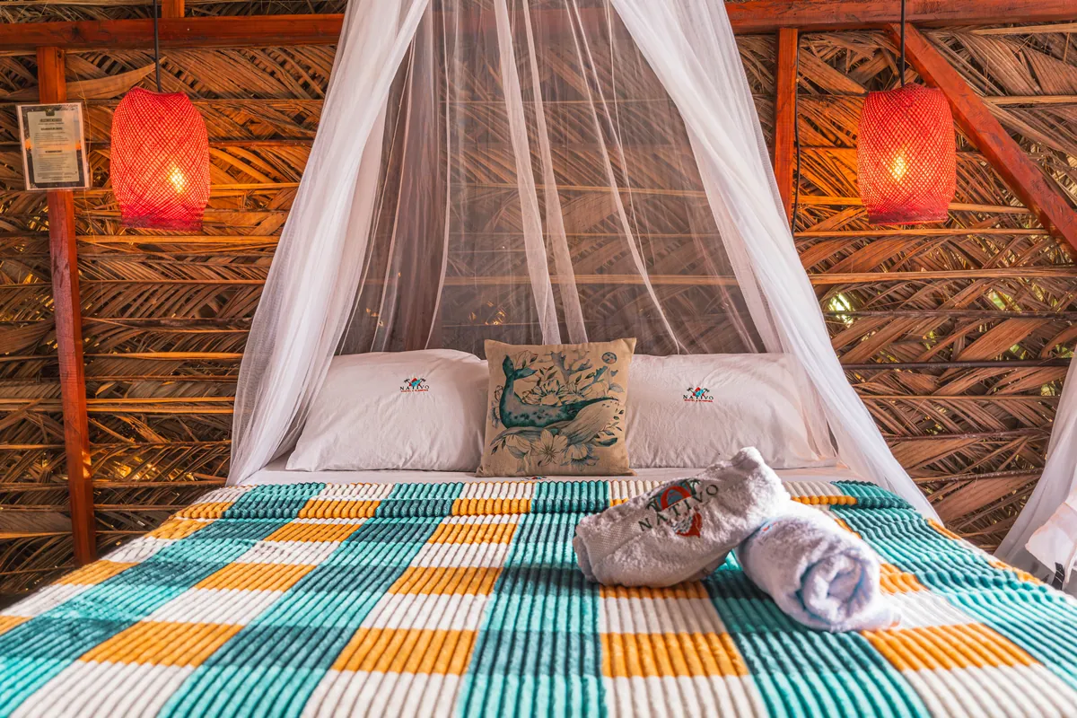 Cama del Bungalow Premium con mosquitero y lámparas cálidas en Nativo