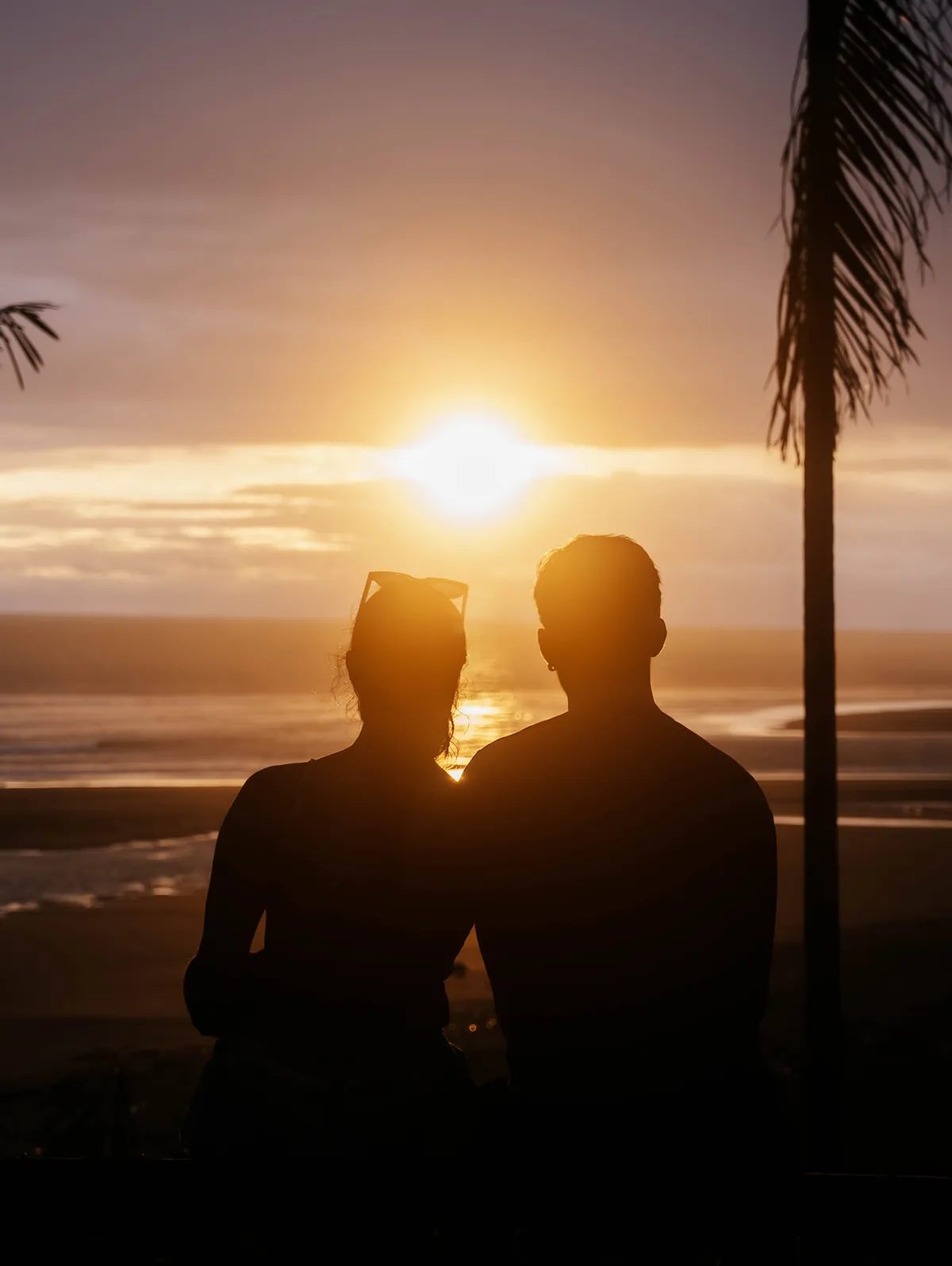 Pareja abrazada viendo el atardecer frente al mar en Nativo